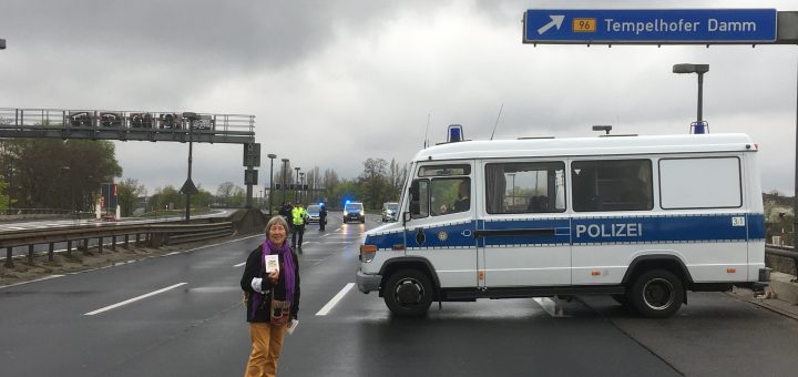 Irma und der Klimaaktivismus. Irma steht auf der Autobahn neben einem Polizeiauto auf einer Demonstration