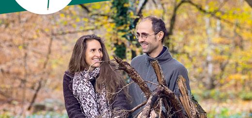 Julian und Simone sitzen vor einem Wurzelballen eines umgekippten Baumes