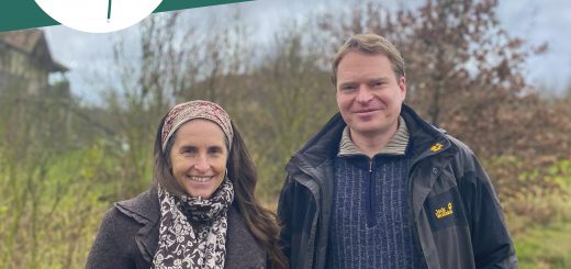 Simone und Daniel stehen in der NAtur udn schauen freundlich in die Kamera