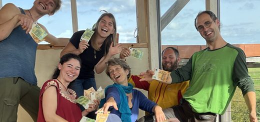Eine Gruppe von jungen und alten Menschen posiert mit Geldscheinen in den Händen und lachen.
