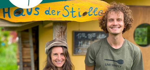 Simone und Jakob sehen vor dem Haus der Stille in Sieben Linden. Hinter ihnen hängt ein gelbes Schild mit der Aufschrift "Haus der Stille"