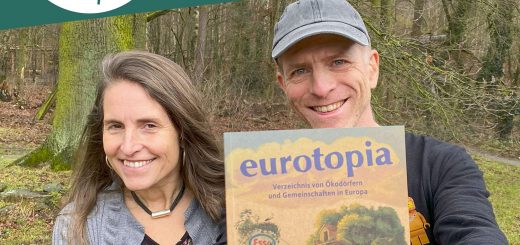 Micha hält die neue Ausgabe vom eurotopia Verzeichnis in die Kamera. Daneben steht Simone