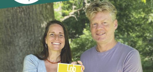 Christian Felber und Simone Britsch stehen in der Natur und halten ei Buch vor sich.