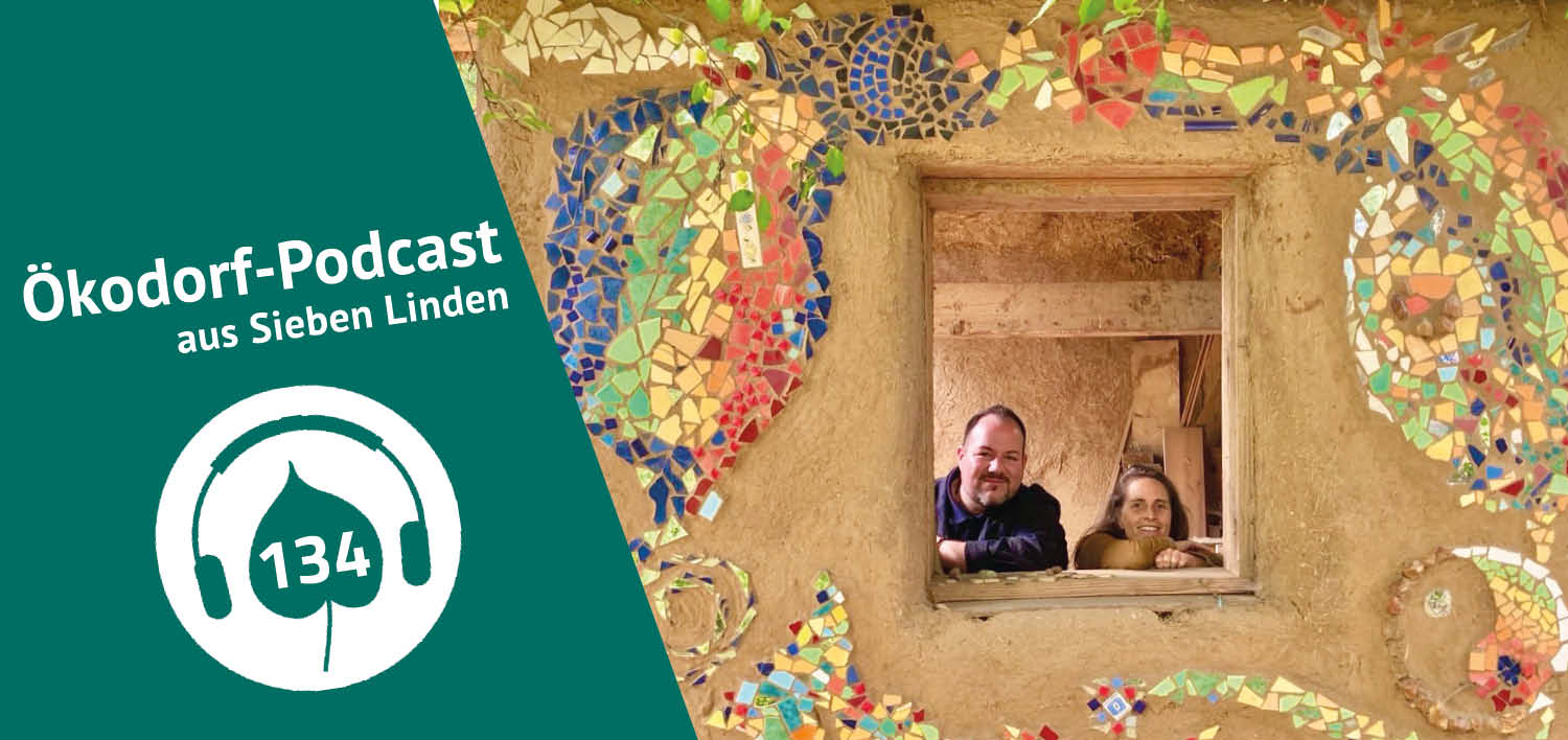 Simone Britsch und Patrick Knobbe-Berlt lächeln aus einen Fenster in einem Lehmballen-Strohbau in die Kamera.