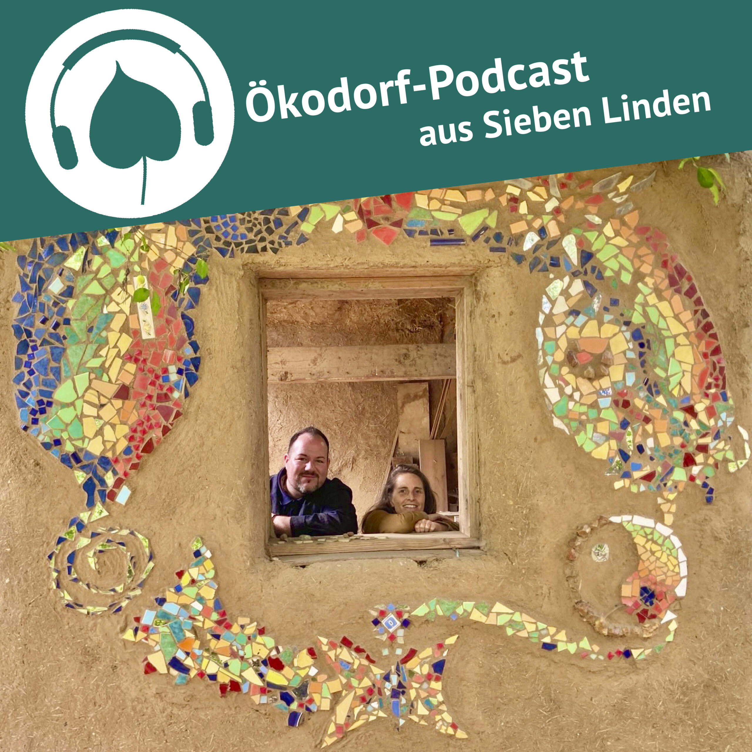 Simone Britsch und Patrick Knobbe-Berlt lächeln aus einen Fenster in einem Lehmballen-Strohbau in die Kamera.