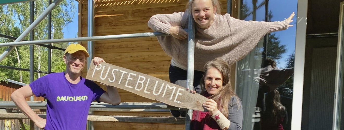 Podcast-Cover: Simone mit Michael Würfel und Gloria Kison vor dem neuen Haus "Pusteblume".