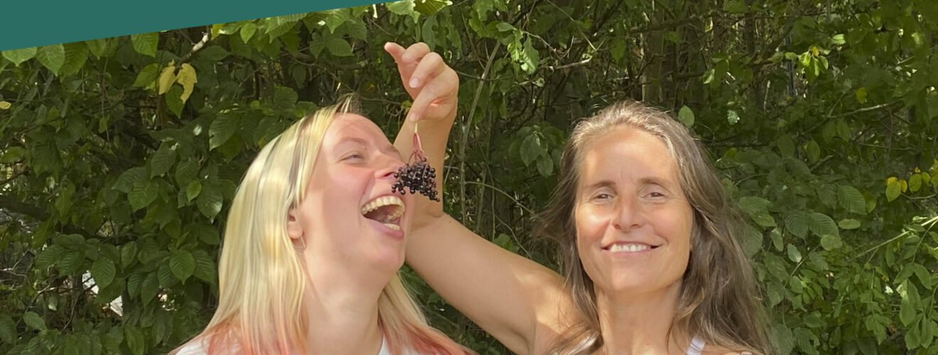 Podcast-Cover: Simone und Annika albern rum und Simone füttert Annika mit Trauben.